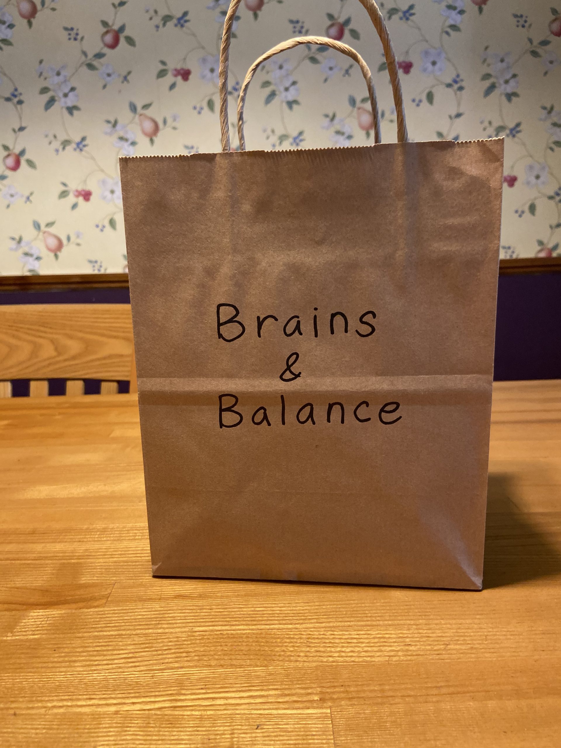 A photo of a brown paper bag with "Brains & Balance" written on the bag