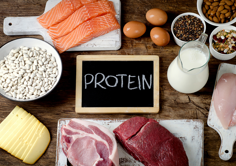 Arrangement of proteins on a table with the word "protein" written a chalkboard 