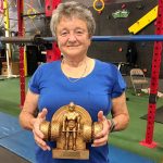 Barb holds a weightlifting trophy