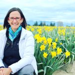 Nurse Nicole Vienneau sits smiling in a field of daffodils