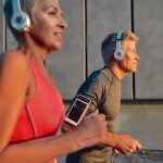 a middle-aged woman and middle-aged man running with headphones on