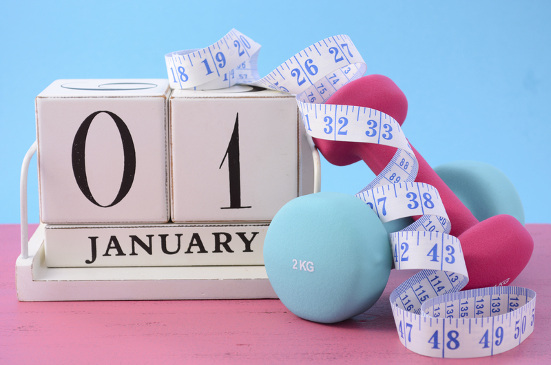 Measuring tape next to a block calendar that says Jan 01 and dumbbells.