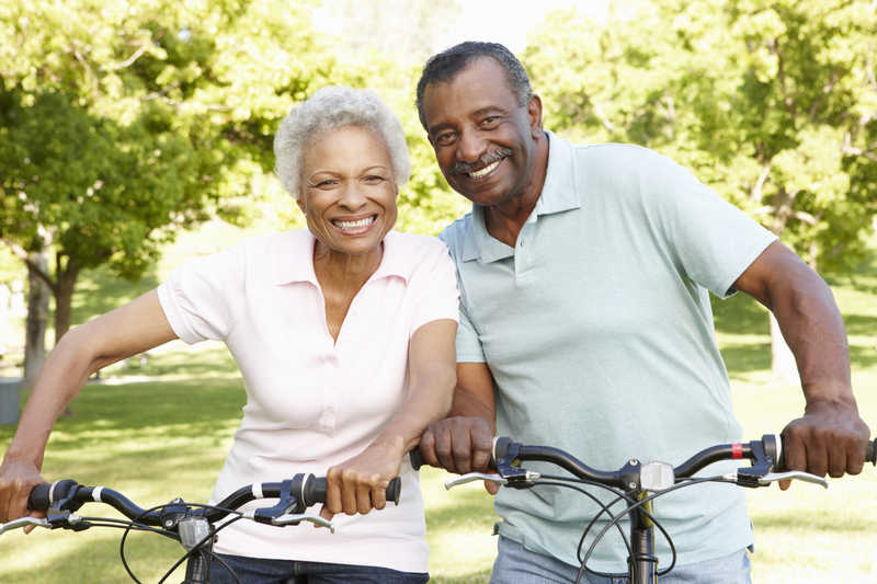 Smiling older couple outside on bicycles. 