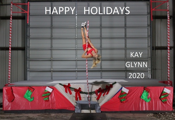 Blonde women hanging upside down on a rope in front of a Christmas themed stage, with the text "Happy Holidays, Kay Glynn 2020" on top