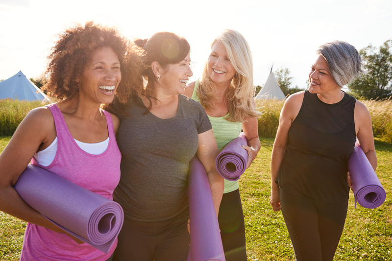Middle aged women outside, walking together with fitness mats