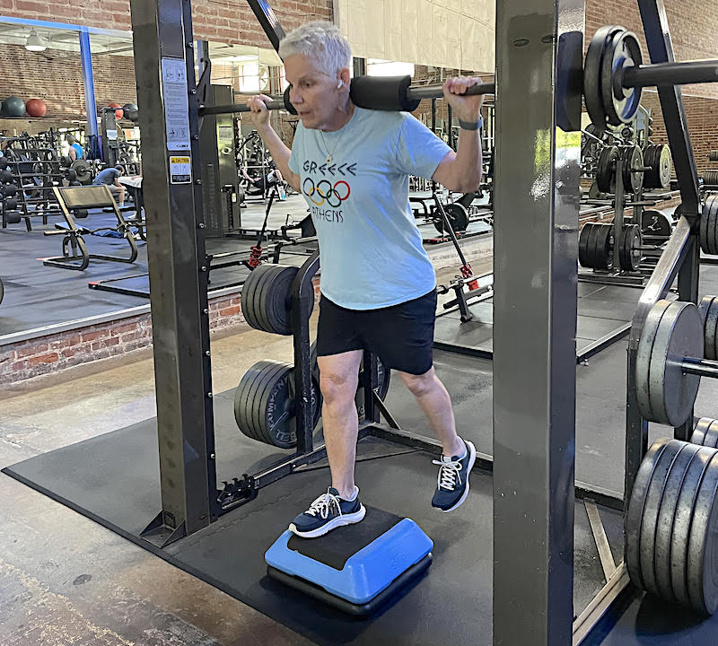 Elderly person at a gym lifting on one foot.