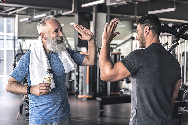 Two men at the gym high-fiving each other