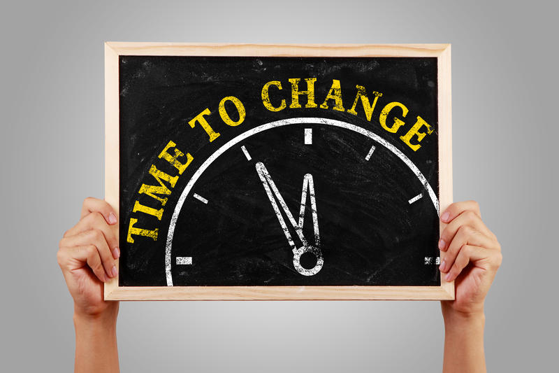Hands holding up a chalk board that has a clock and the words "Time to Change" on it.